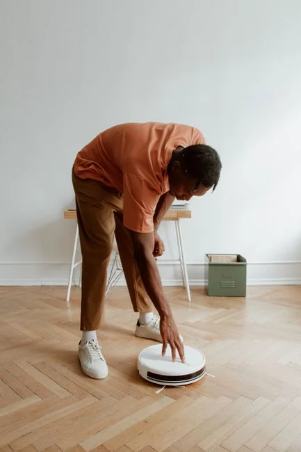 A man in a blue t-shirt cleaning large glass pane with a squeegee indoors.