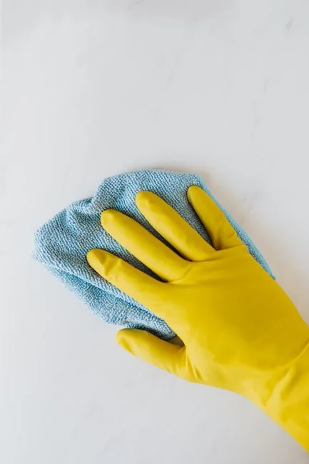 A man cleaning a glass door indoors using a spray bottle and cloth.